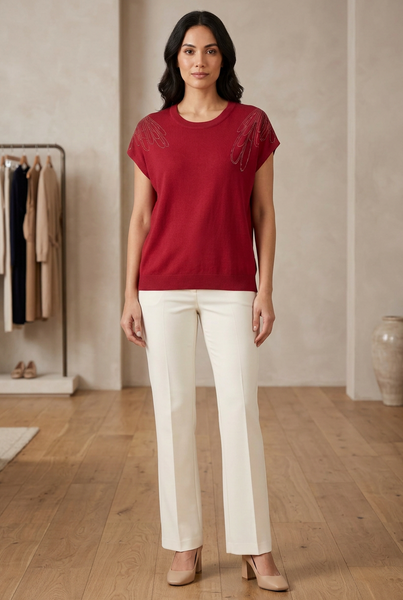 AI-generated full-body model wearing a red knit top with sparkling shoulder embellishments and ivory trousers