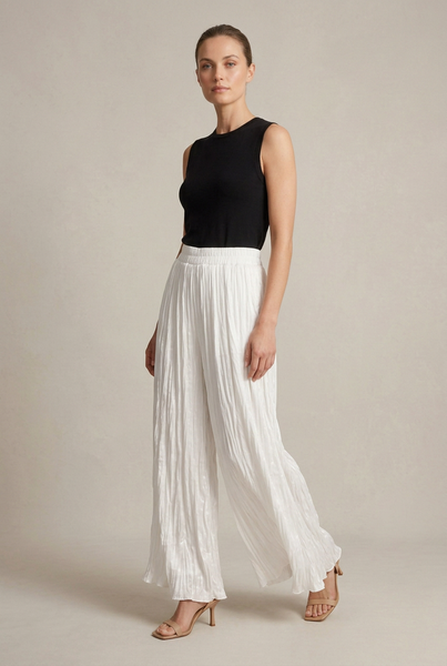 AI-generated full-length model in a three-quarter pose wearing white crinkled palazzo pants, a black top and neutral heels