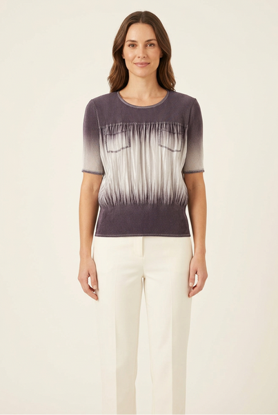 Model wearing a short purple and silver-grey ombre pleated top with chest pockets and ivory trousers