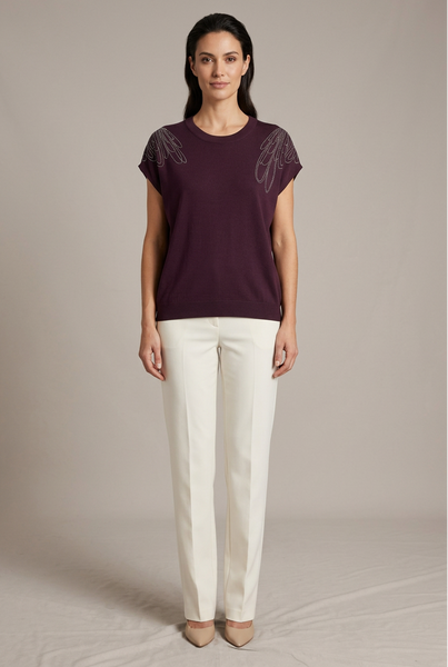 AI-generated full-body model wearing a deep purple knit top with silver looping shoulder embellishments and ivory trousers