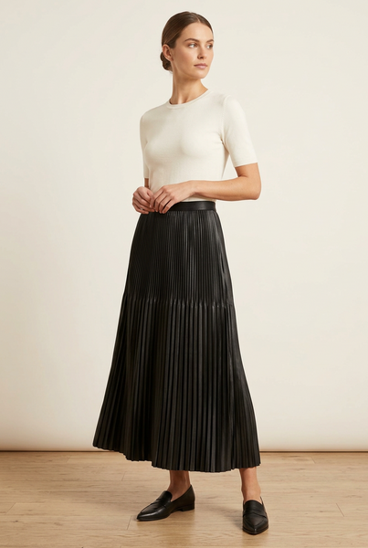 Model wearing a black accordion pleated skirt with an ivory top.